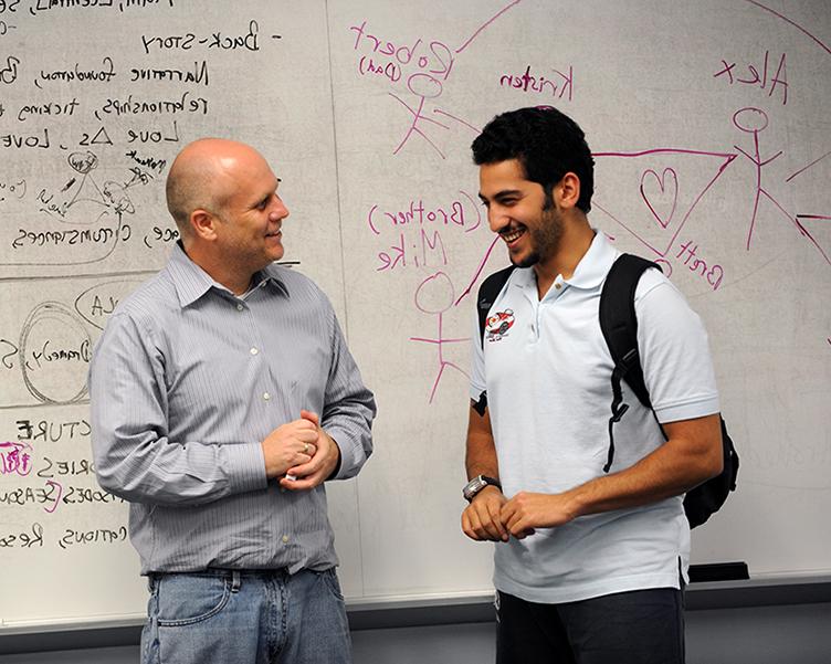 Professor and student talking near the front of the classroom.